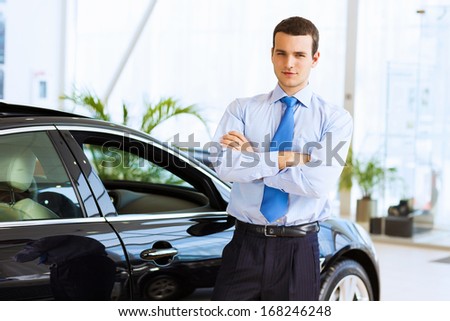 Image of handsome young businessman in suit standing near car