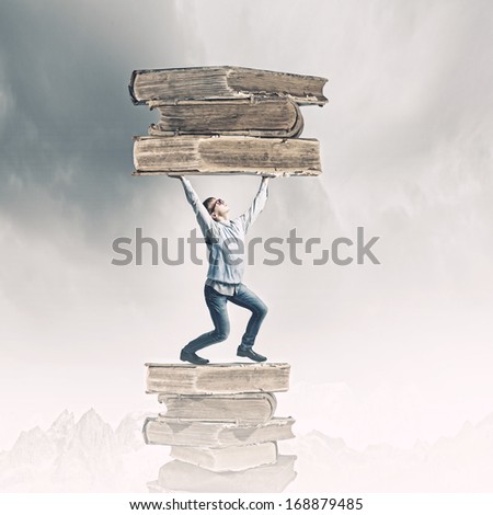 Young man holding huge book above head