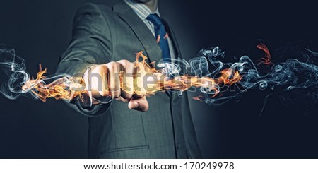 Businessman holding fire flames in fist. Power and control