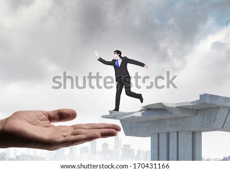 Image of running businessman at the edge of bridge supported by human hand