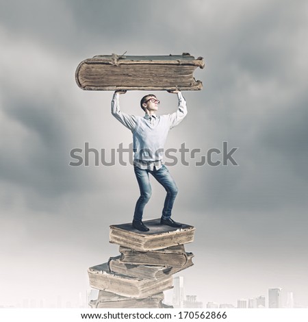 Young man holding huge book above head