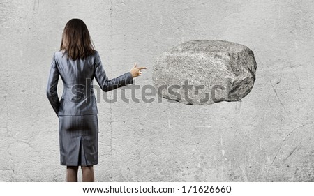 Businesswoman pointing with finger at huge stone