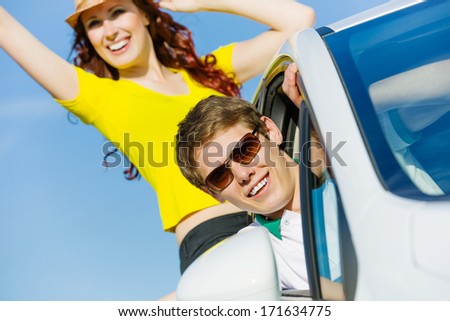 Young people leaning out of car and waving happily