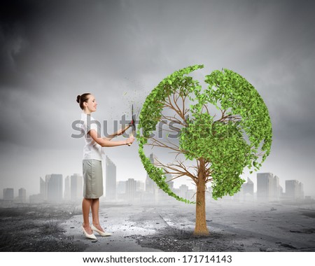 Young businesswoman cutting tree with scissors in shape of Earth planet