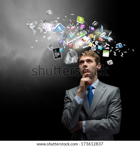 Young thoughtful businessman looking up with hand on chin