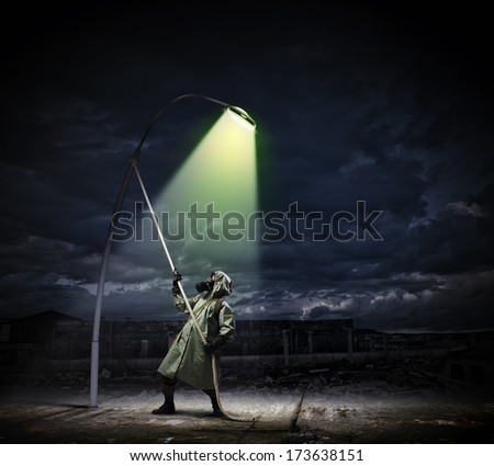 Man in gas mask and camouflage standing under street light
