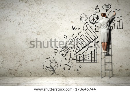 Image of businesswoman standing on ladder and drawing on wall