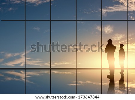 Silhouettes Of Businesspeople Standing Against Panoramic Office Window