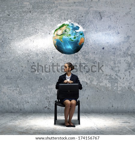Young upset businesswoman with suitcase sitting on chair. Elements of this image are furnished by NASA
