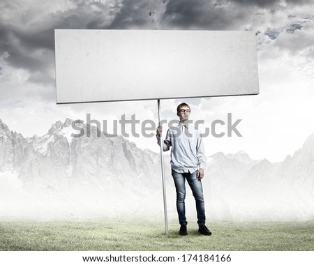 Young man in glasses holding blank banner. Place for text