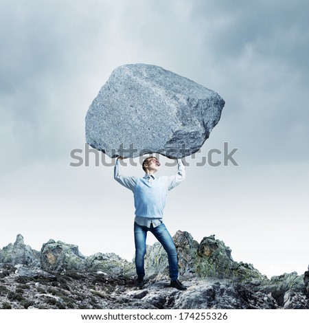 Young strong man holding huge stone above head
