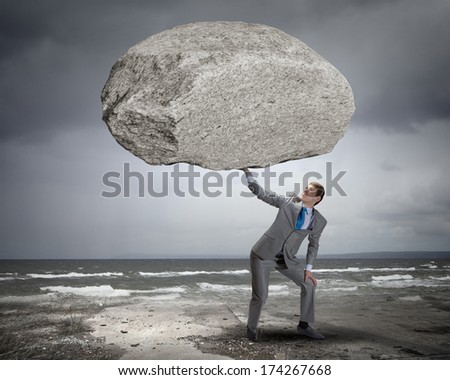 Powerful businessman holding huge stone above head