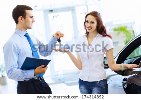 Attractive woman at car salon with consultant choosing a car