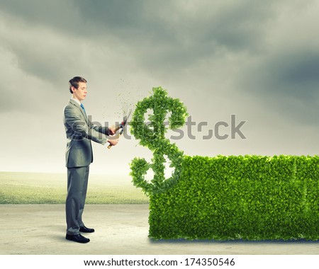 Young Businessman Cutting Bush In Shape Of Dollar