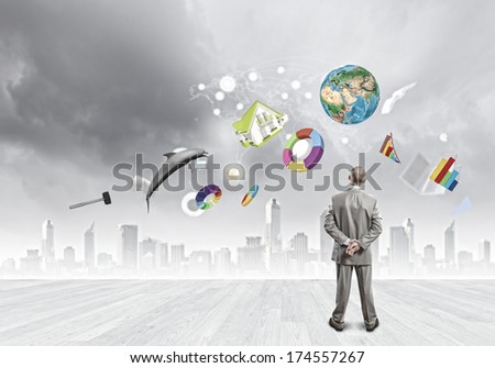Back view of confident businessman looking at city with items flying in air. Elements of this image are furnished by NASA