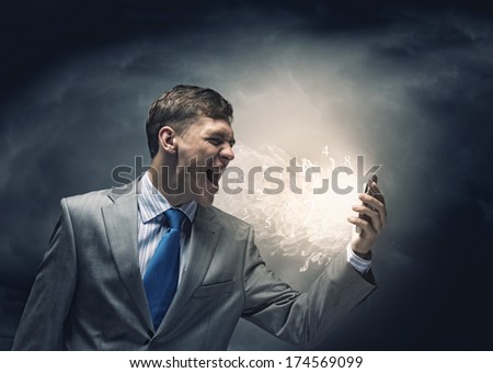 Angry businessman screaming i to mobile furiously phone