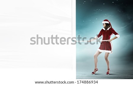Girl in Santa costume pulling white blank banner. Place for text