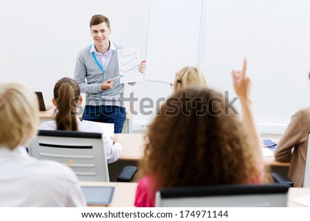 Young teacher in classroom standing in front of class