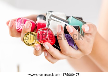 Close up of woman hands with nail polishes of different colors