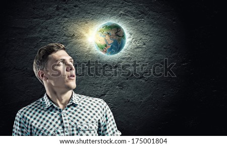 Young man against dark background and Earth planet image. Elements of this image are furnished by NASA