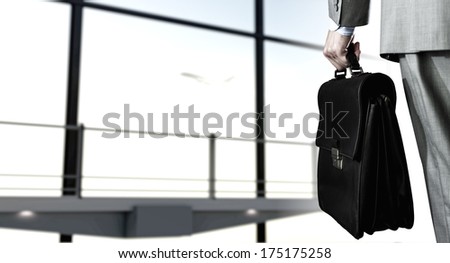 Back view of businessman at airport with suitcase in hand