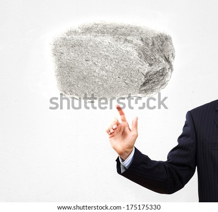 Businessman in suit pointing at huge stone
