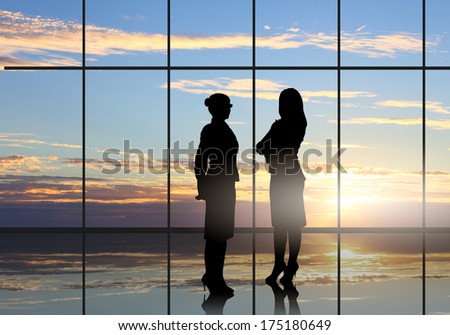 Silhouette of businesswoman against panoramic office window