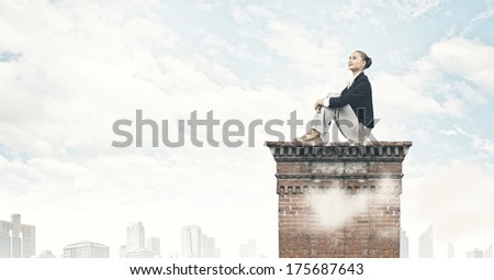 Young pretty lady sitting on top of building and dreaming