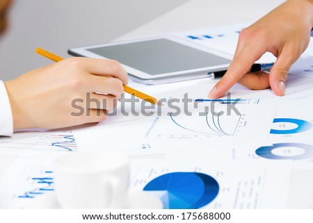 Close up of human hands and documents with graphs and diagrams