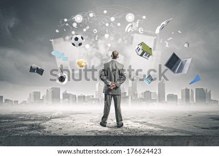 Back view of confident businessman looking at city with items flying in air