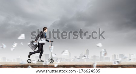 Young businessman riding scooter on roof of building