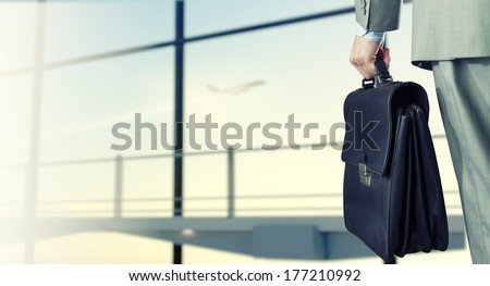 Back View Of Businessman At Airport With Suitcase In Hand