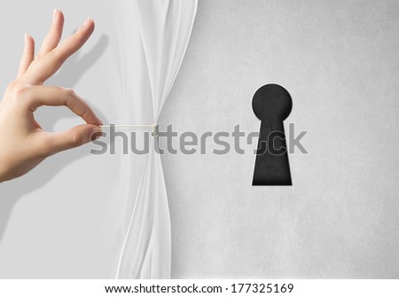 Close up of hand opening white curtain with keyhole behind it