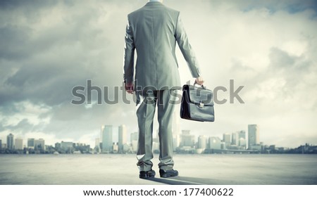 Back view of businessman on road with suitcase in hand