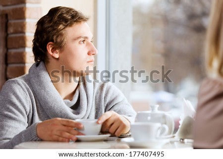 Young man sitting at table with girl at cafe