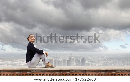 Young attractive lady sitting on top of building
