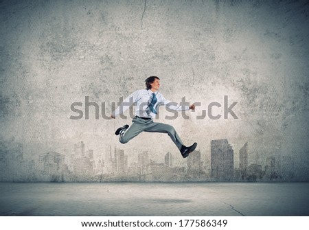 Young businessman in jump against city background