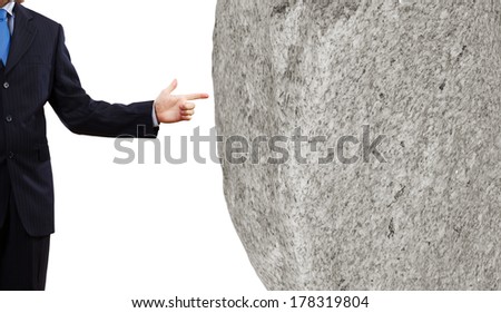 Businessman in suit pointing at huge stone