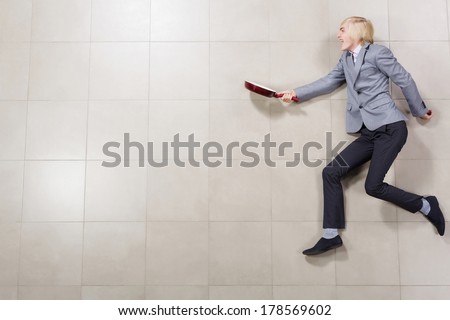 Funny image of young running businessman with pan in hand