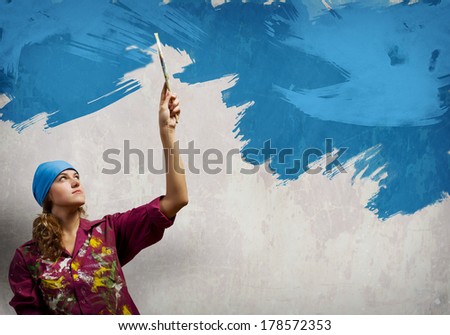 Young woman painter in bandana with paintbrush in hand