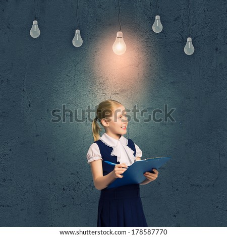 Cute school girl against grey wall with bulbs hanging above