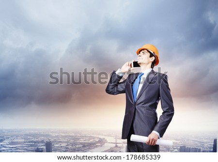 Young man engineer in helmet talking on mobile phone