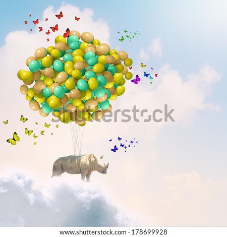 Rhino flying high in sky on bunch of colorful balloons