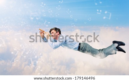 Young businessman flying in sky and playing fife