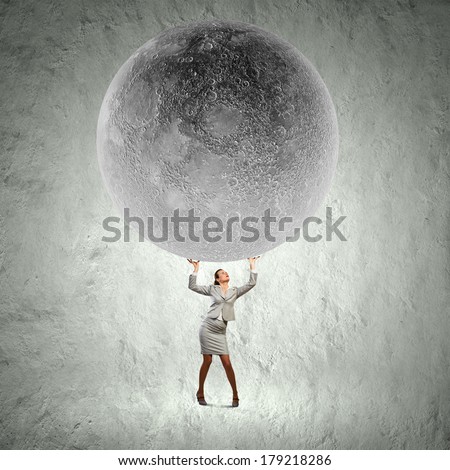 Conceptual image of businesswoman holding huge moon above head