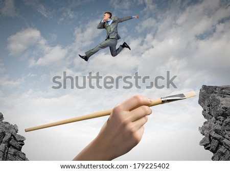 Young businessman in suit jumping over mountain gap