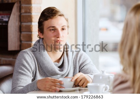 Young man sitting at table with girl at cafe