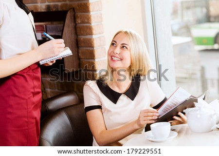 Young attractive woman making order at restaurant