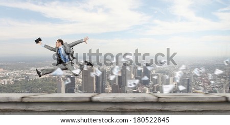 Young cheerful businessman in jump against city background