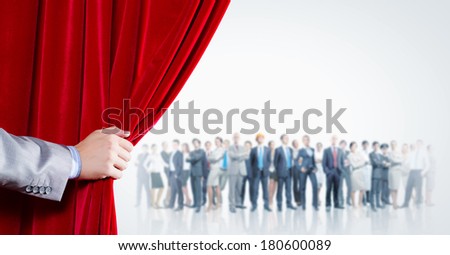 Hand of businessman opening red velvet curtain